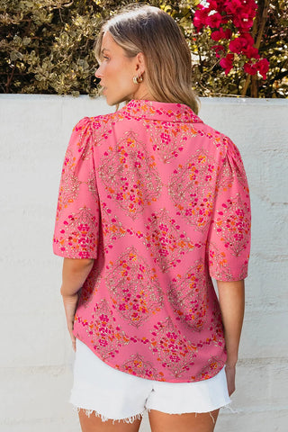 Back view of a woman wearing a vibrant floral geometric Morning Glory Blouse with puffed sleeves.