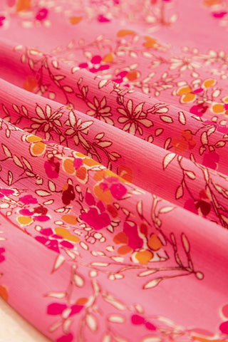 Close-up of the Morning Glory Blouse, showing its vibrant floral geometric pattern on pink fabric.