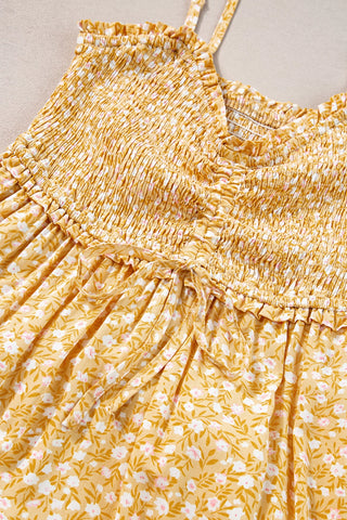 Close-up of a yellow floral maxi dress with a smocked bodice and a tie detail at the waist.