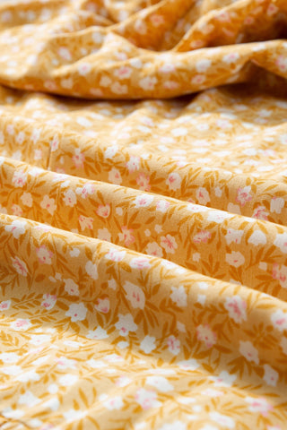 Close-up of the Open Fields Maxi Dress fabric, showing a yellow floral maxi dress with small white and pink flowers.