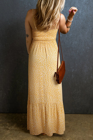 Back view of a woman wearing a yellow floral maxi dress with thin straps and a smocked bodice.