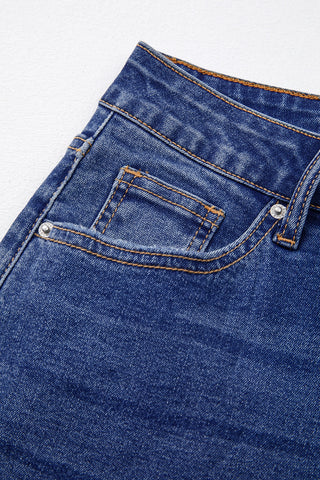 Close-up of the front pocket and waistband of Open Sky Bootcut Jeans with orange stitching and silver rivets.