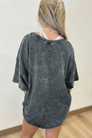 Back view of a woman wearing an Outlaw Washed Oversized Top, a dark gray washed distressed tee with a relaxed fit.