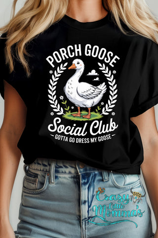 Woman in black tee with "Porch Goose Social Club" text, a white goose, and a wreath design.
