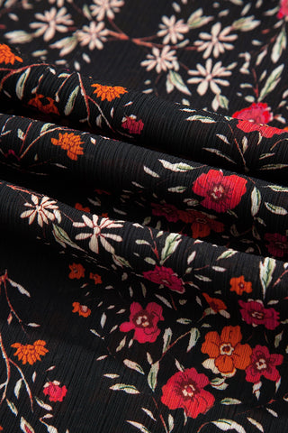 Close-up of the Porchlight Bloom Button Top, showing its black fabric with a vibrant floral pattern.