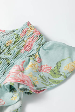 Close-up of the Prairie Bloom Smocked Dress, showing smocking and a floral pattern on light blue fabric.