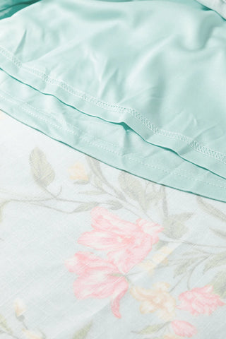 Close-up of the Prairie Bloom Smocked Dress, showing the light blue fabric with pink floral print and smocking.