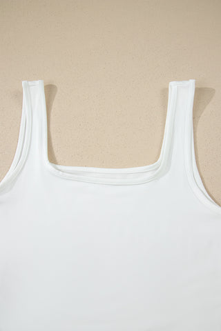 Close-up of a white Prairie Lace Mesh Top with a square neckline, laid flat on a speckled beige surface.