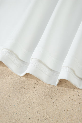 Close-up of the white Prairie Lace Mesh Top's hem, showing delicate stitching and fabric folds.