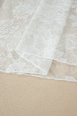 Close-up of white floral lace mesh fabric, folded on a beige surface.