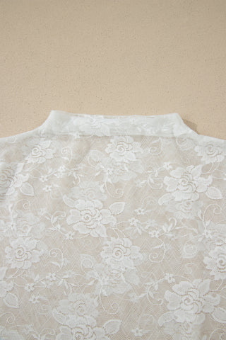 Close-up of a white floral lace mockneck top, showcasing the intricate flower patterns and mesh fabric.