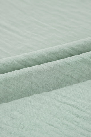 Close-up of the soft, light green fabric of the Prairie Ruffle Blouse, showing its textured weave.