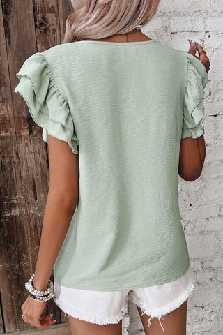 Back view of a woman wearing a light green Prairie Ruffle Blouse with layered ruffle sleeves.