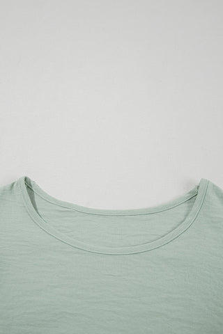 Close-up of the light green Prairie Ruffle Blouse, showing the round neckline and textured fabric.