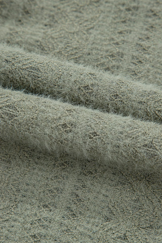 Close-up of the soft, fuzzy texture of the sage ruffle button top fabric, showing its intricate weave.