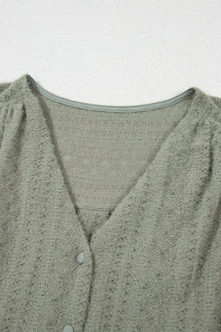 Close-up of a sage ruffle button top, showing the textured fabric, V-neckline, and light green buttons.