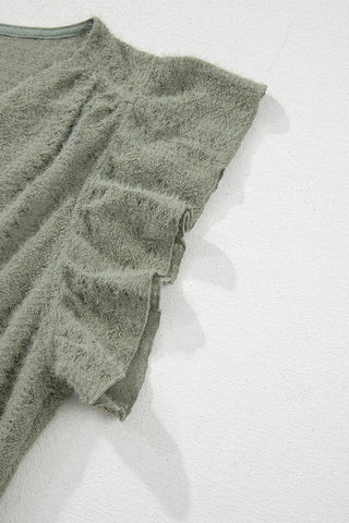 Close-up of a sage ruffle button top, showing the soft, fuzzy texture and ruffled sleeve detail.