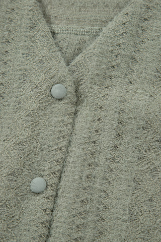 Close-up of a sage ruffle button top, showing the soft, textured fabric and two light gray buttons.