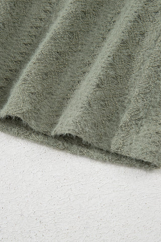 Close-up of the soft, textured fabric of the sage ruffle button top, showing its fuzzy detail and folds.