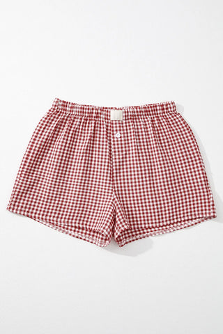 Red and white gingham shorts with an elastic waistband and a single white button closure, laid flat on a white surface.
