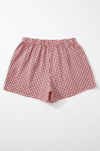 Red and white gingham shorts with an elastic waistband, laid flat against a white background.