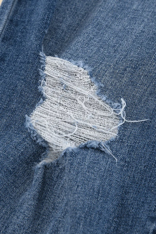 Close-up of blue Ranch Hand Distressed Jeans with a ripped detail showing white threads.