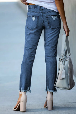 Back view of a woman wearing Ranch Hand Distressed Jeans with frayed hems and distressed back pockets.
