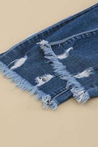 Close-up of blue Western distressed jeans with frayed edges and rips, showcasing the denim texture.