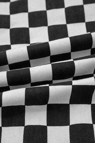 Close-up of black and white checkerboard distressed jeans fabric with visible texture and folds.