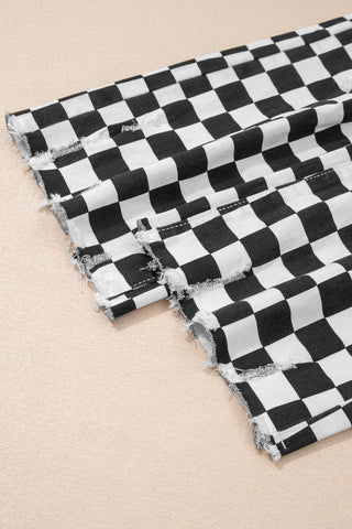Close-up of black and white checkerboard distressed jeans with frayed edges on a beige surface.