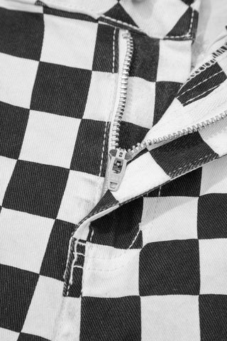 Close-up of the zipper and black and white checkerboard distressed jeans fabric.