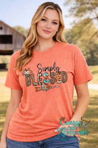 A woman in an orange tee with "Simply Blessed" in patterned letters, adorned with arrows and floral designs.