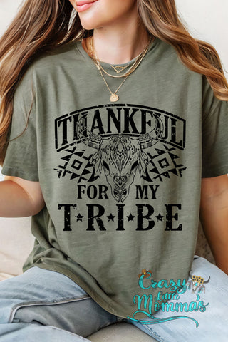 A woman wears a green "Thankful for my Tribe" tee with a steer skull and Western-inspired pattern.