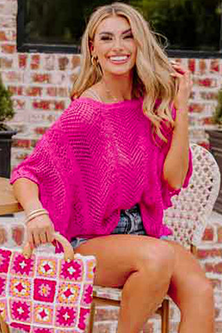 Smiling woman in a bright pink Boho Chevron Knit Top with a loose fit and chevron pattern, holding a colorful bag.