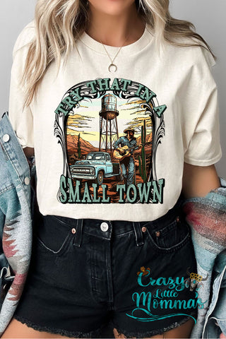 A woman wears a "Try That in a Small Town" country western tee with a desert scene and a guitarist.