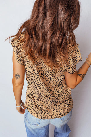 Back view of a woman wearing a tan cheetah print ruffle blouse with light wash jeans.