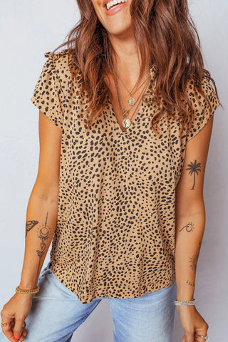 A woman wearing a tan cheetah print ruffle blouse with a V-neck and short sleeves.