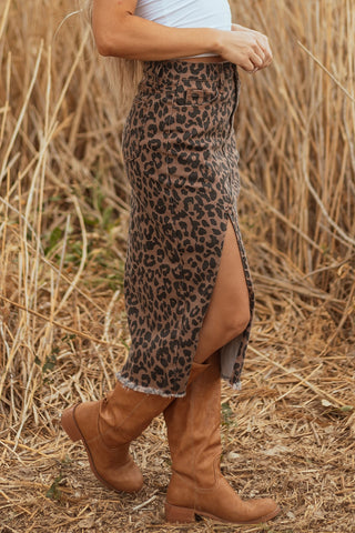 Woman in a Wildcat Midi Denim Skirt with a leopard print, side slit, and frayed hem, walking in tall boots.