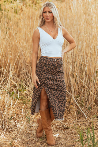 A blonde woman models a leopard print denim skirt with a front slit and frayed hem, paired with a white top.
