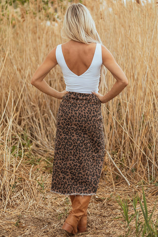 Back view of a woman wearing a Wildcat Midi Denim Skirt with a leopard print and frayed hem.