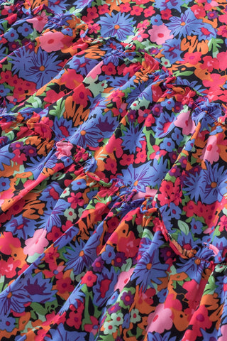 Close-up of a vibrant floral babydoll ruffle top with colorful wildflowers and ruffled tiers.
