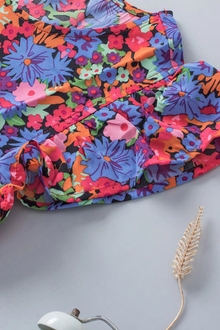 Close-up of a vibrant floral babydoll ruffle top with blue, pink, orange, and green wildflowers.
