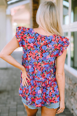 Back view of a blonde woman wearing a vibrant floral babydoll ruffle top with blue, pink, and red flowers.