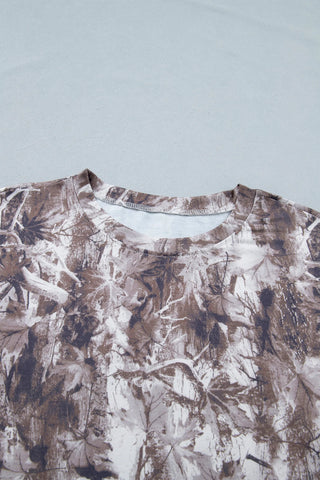 Close-up of an earthy camo crewneck tee with a brown, white, and gray leaf and branch pattern.