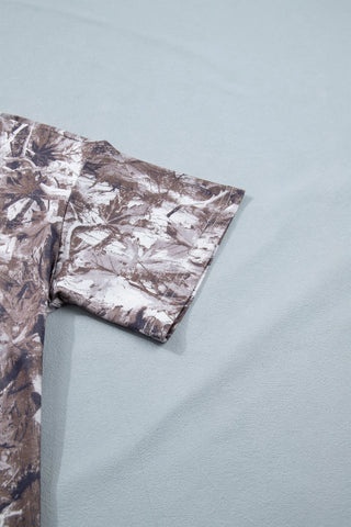 Close-up of a Wildwood Camo Tee sleeve with an earthy camo crewneck tee pattern against a light blue background.