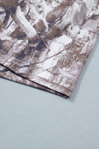 Close-up of the Wildwood Camo Tee, showing the earthy camo pattern and white stitching on the hem.