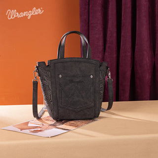 Black Wrangler cowhide tote/crossbody with embossed sides and front pocket, on a table with a magazine.