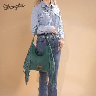 Model holds a turquoise Wrangler studded fringe hobo bag, showcasing its texture and western details.